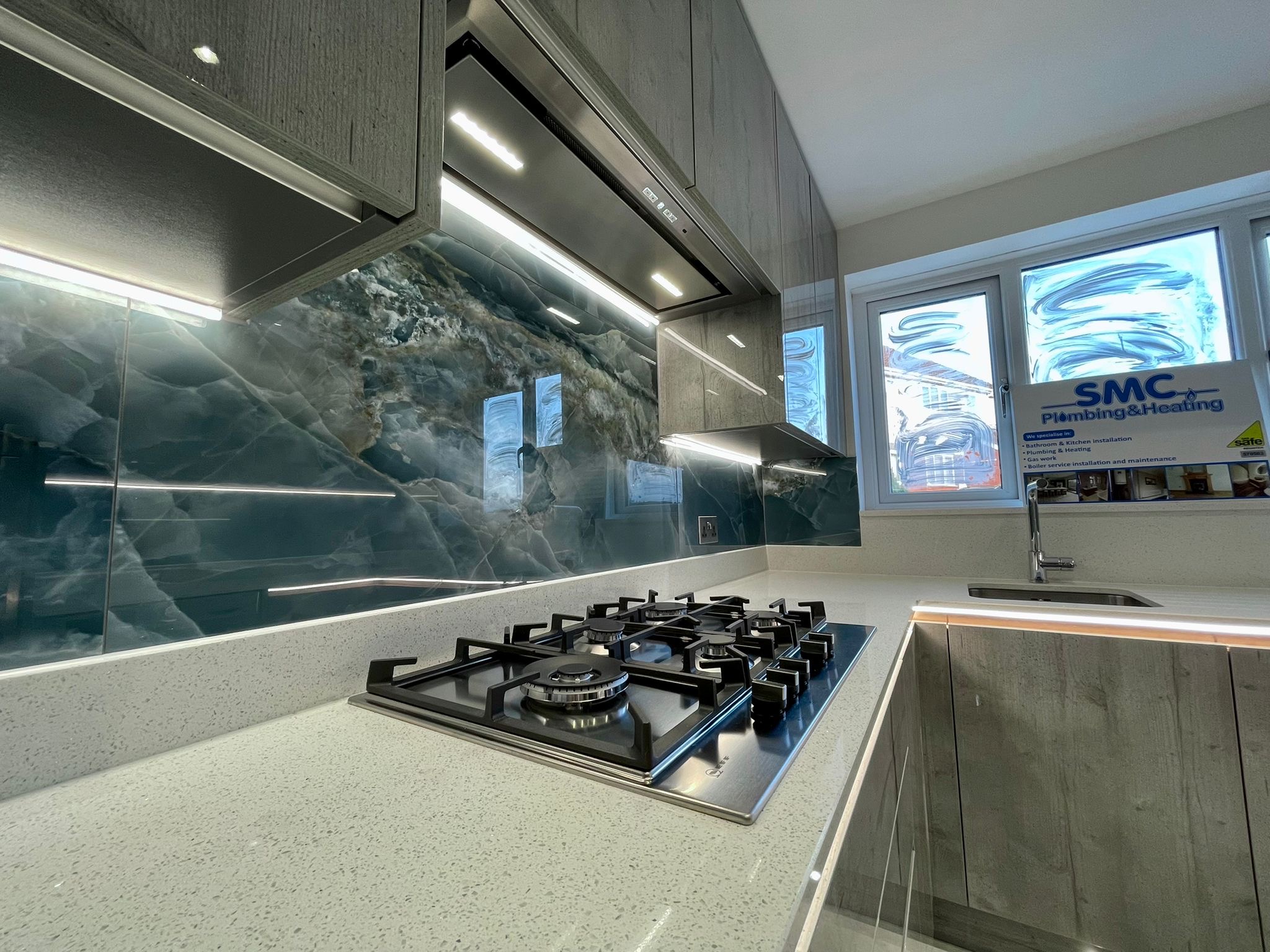 Gas hob and pale worktop with lighting beneath the cabinets and worktop edge