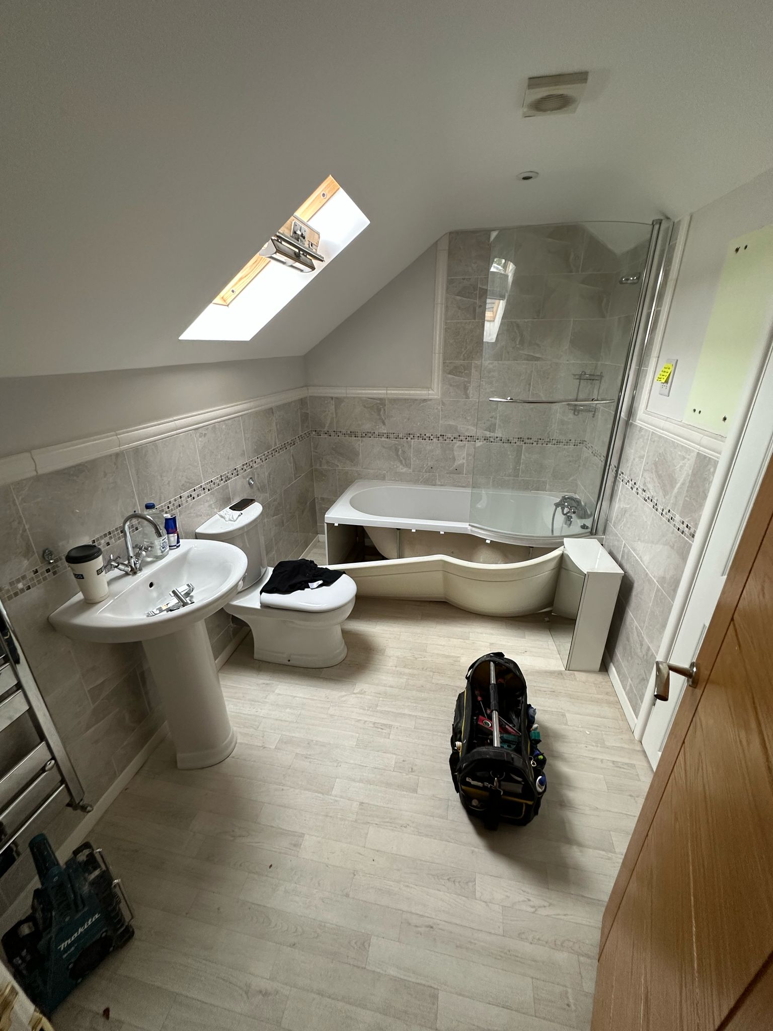 Loft bathroom before renovation, with a pedestal basin and enclosed bath