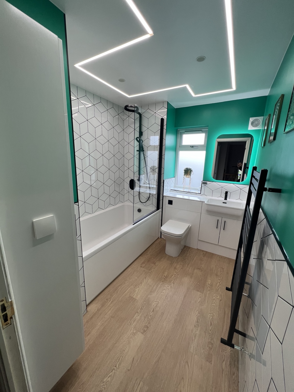 Fitted vanity, teal walls, backlit mirror and coordinated black fittings